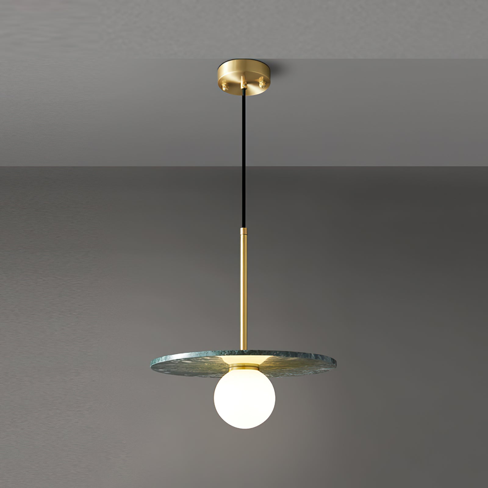 Green marble pendant with a glowing sphere against a grey wall