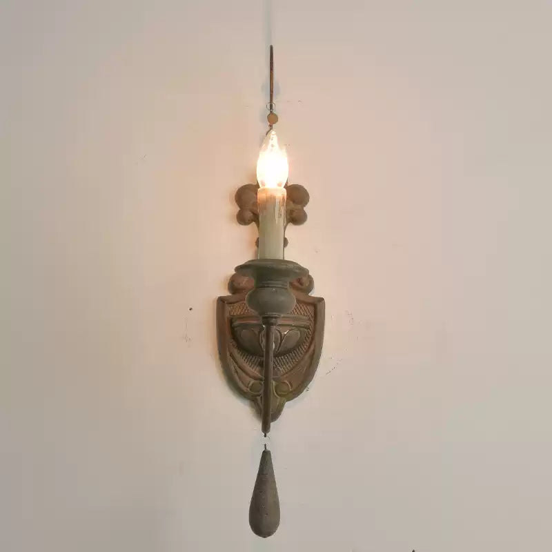 Front view of a single candle-style wall lamp with a decorative backplate
