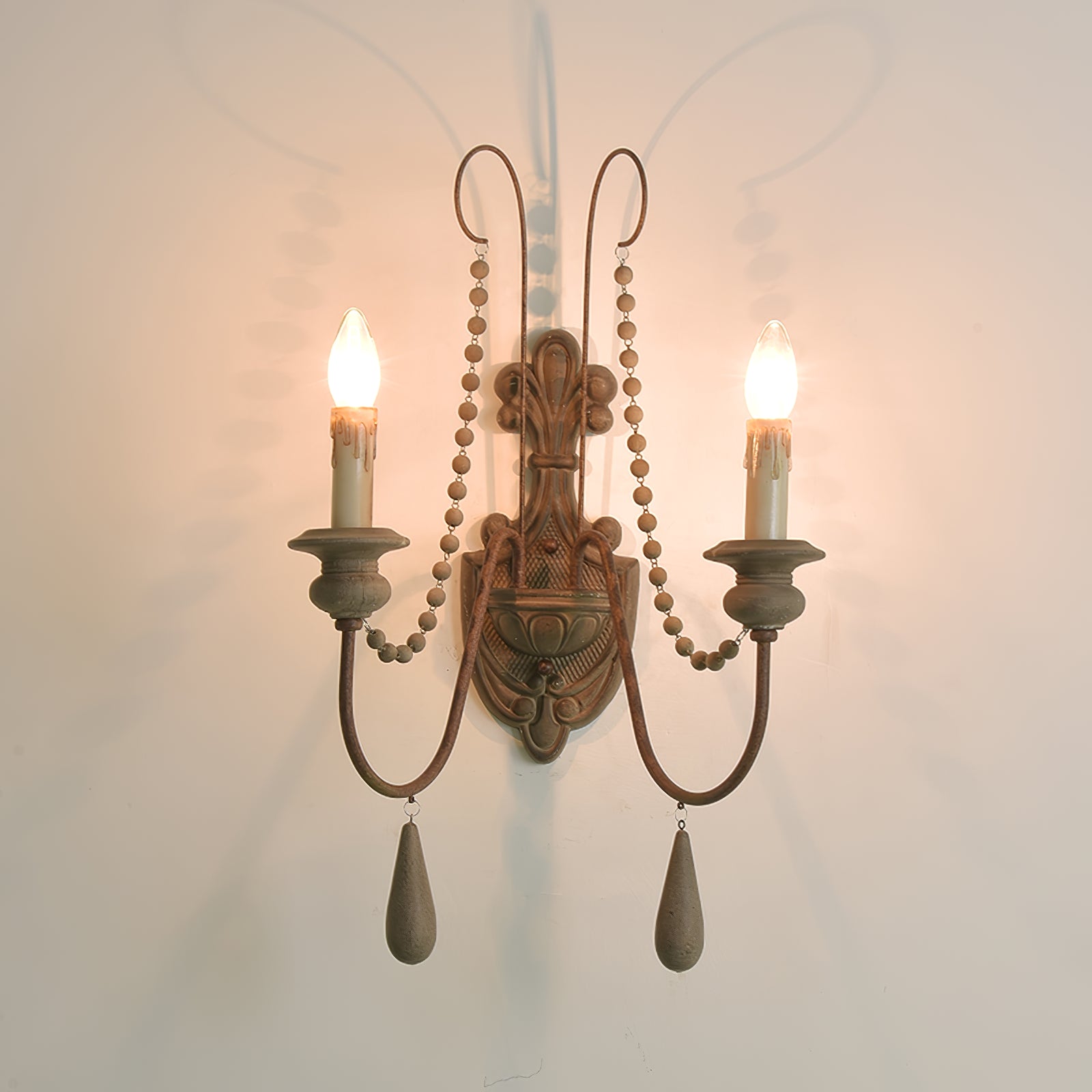 Wood wall sconce with two glowing candle-style lamps and curved arms