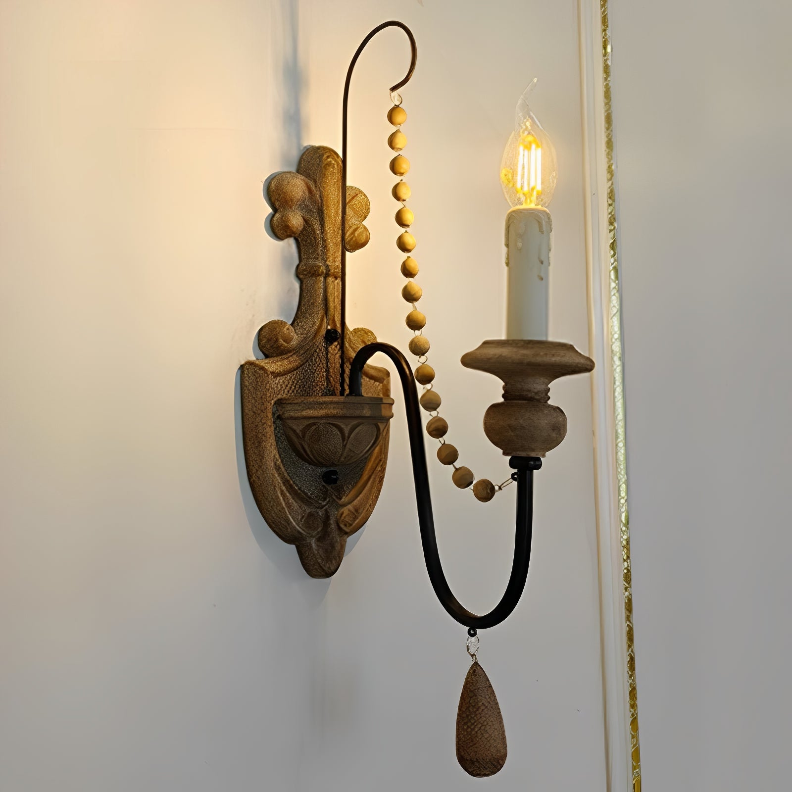 Side view of a single-arm candle wall lamp with hanging bead and teardrop details