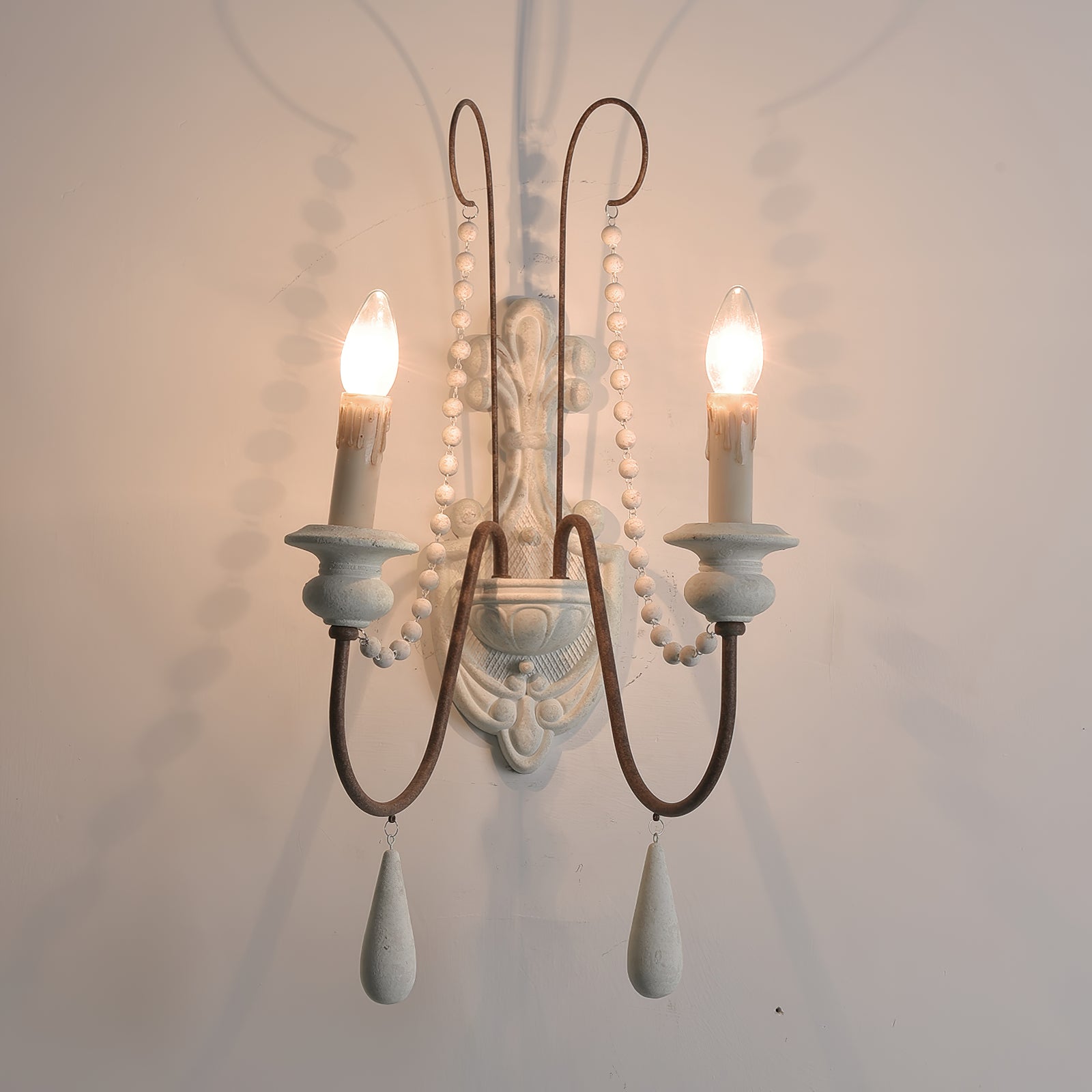 Pale-finish two-light wall sconce with bead strands and hanging teardrops