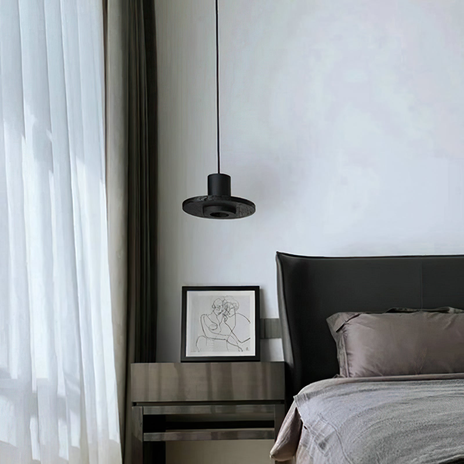 Black pendant beside a grey upholstered bed