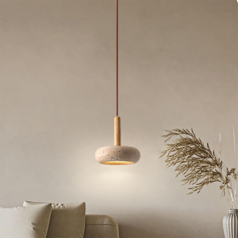 Rounded stone pendant beside a vase of dried grasses
