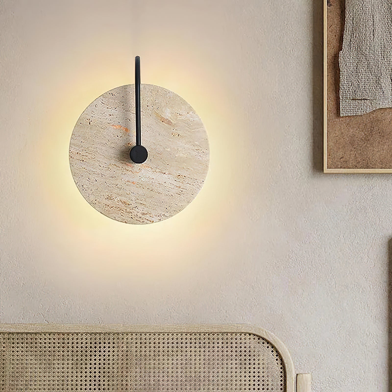 Stone disc wall light above a woven bedroom headboard