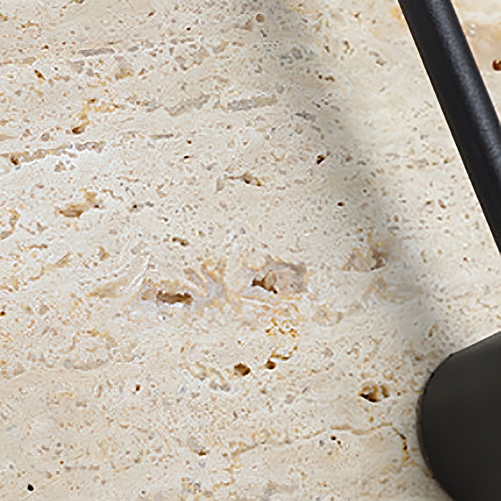 Close-up of porous travertine texture near the black arm