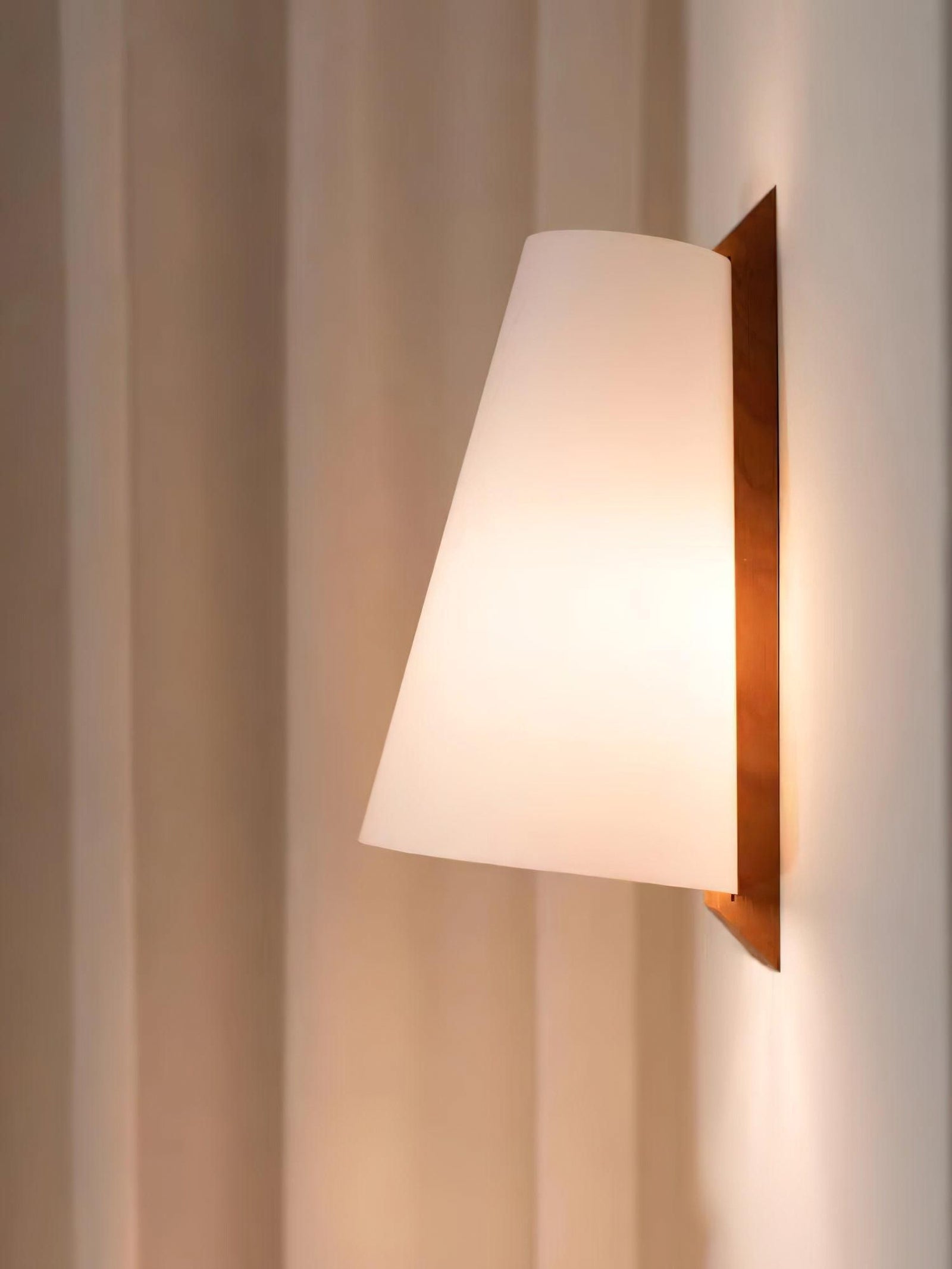 Lupe wall light illuminated beside a curtain