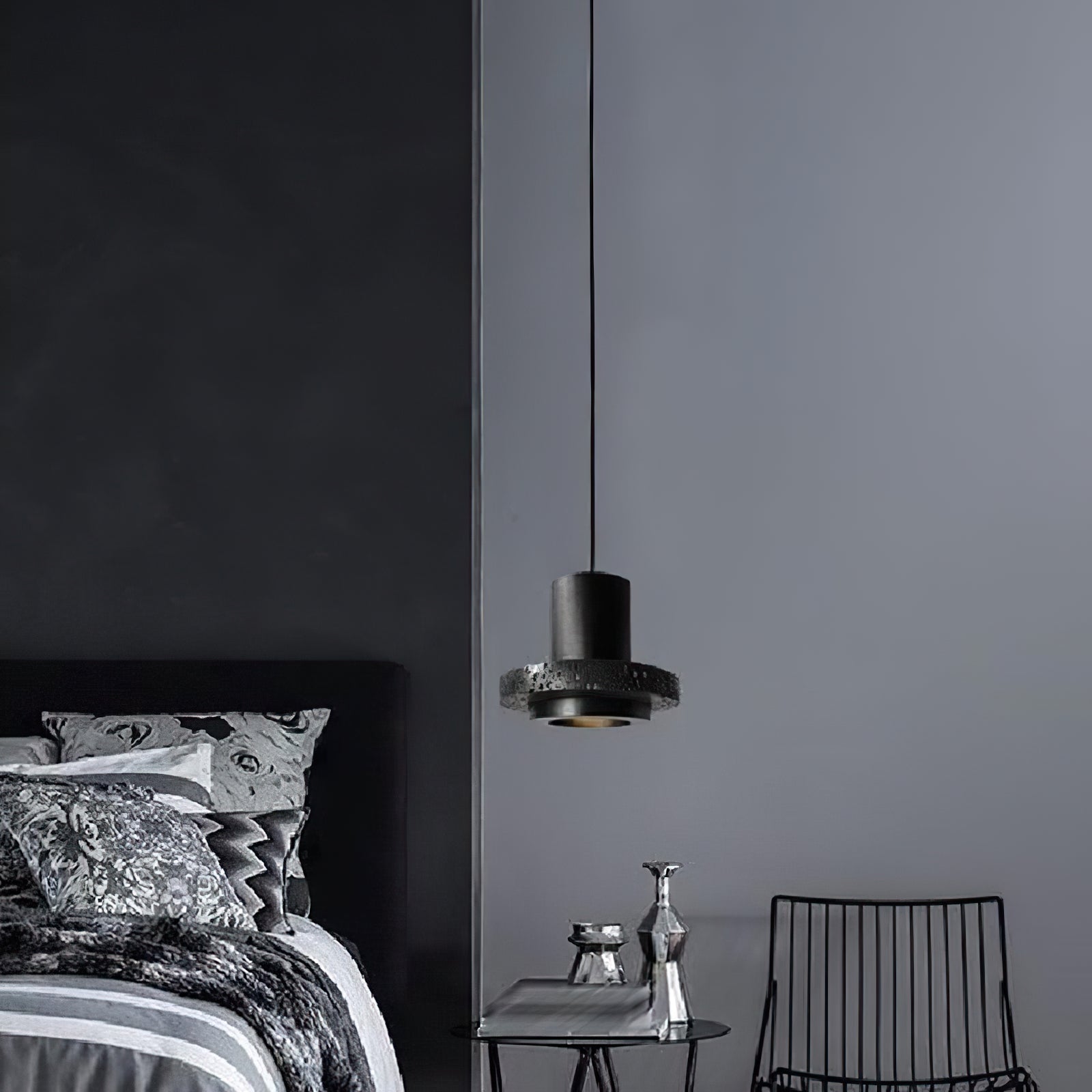 Compact black pendant beside a bed on a dark wall