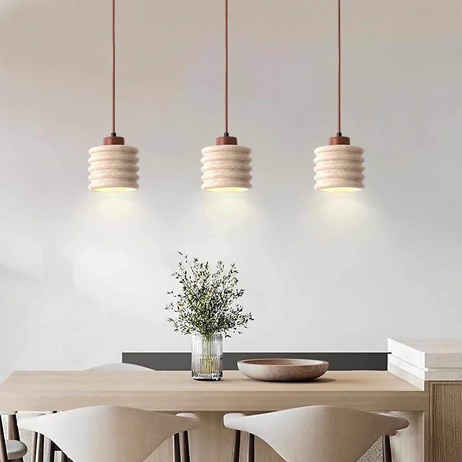 Three ribbed travertine pendants above a dining table
