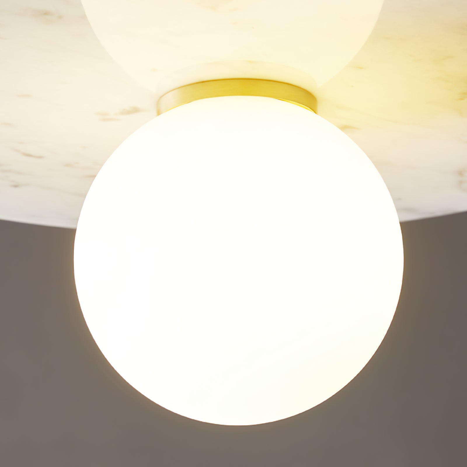 Detail of the illuminated sphere beneath a pale marble disc