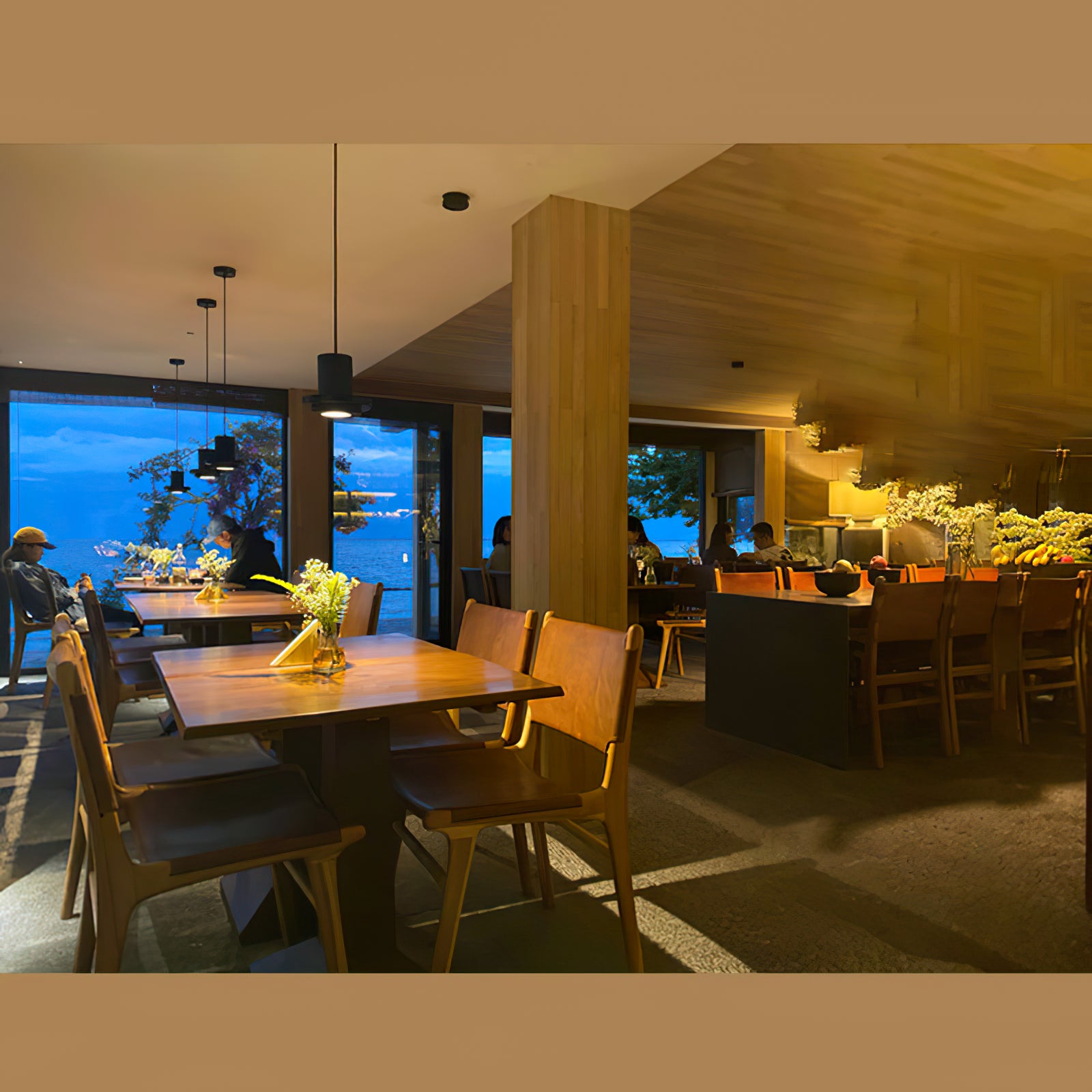 Black pendant lights above dining tables in a warm interior