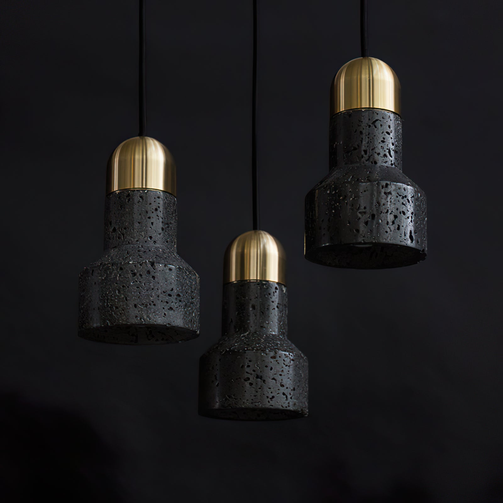 Three black textured pendants with gold-coloured caps at different heights