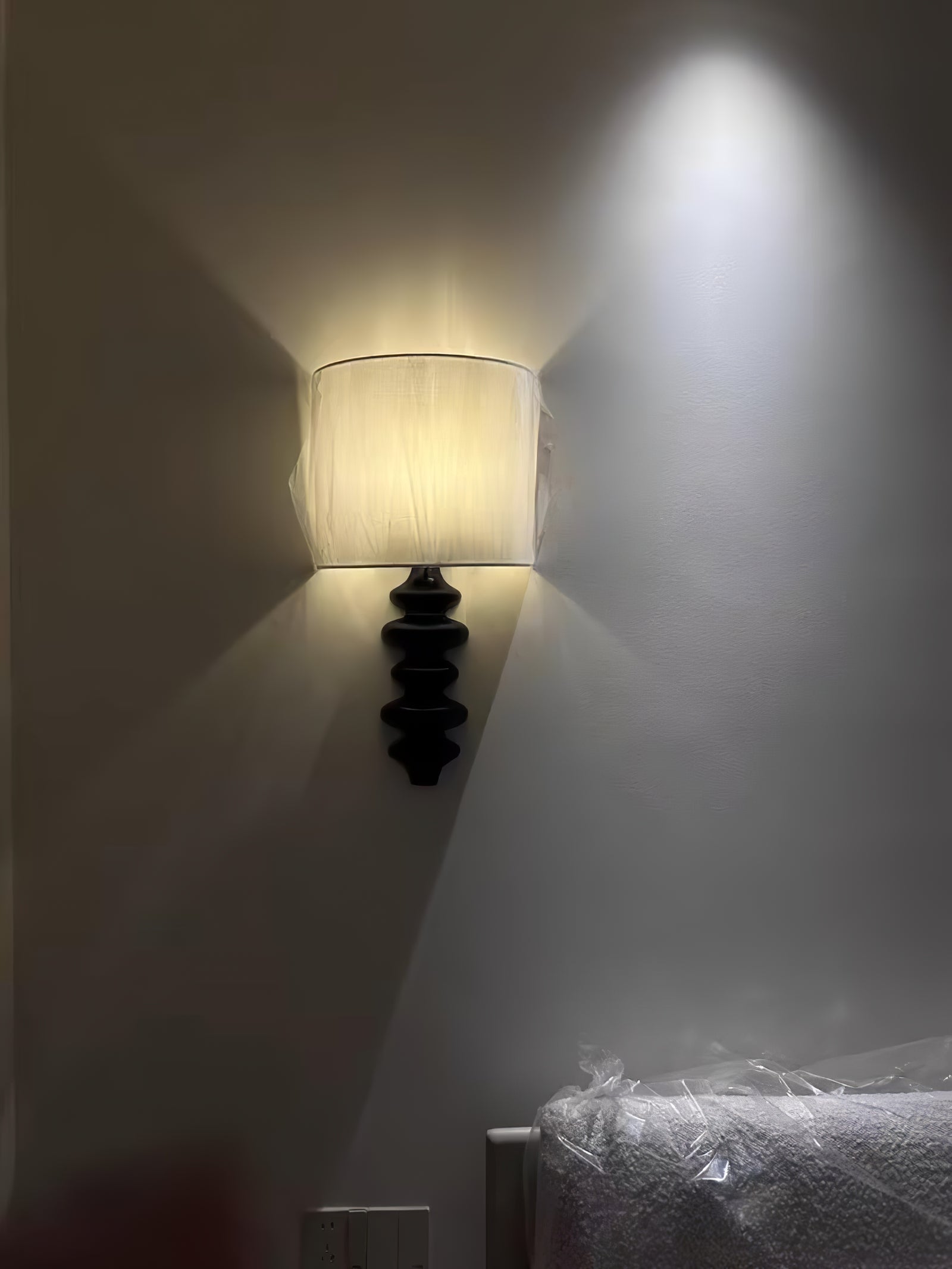 Black Fishbone wall lamp casting light above and below its shade
