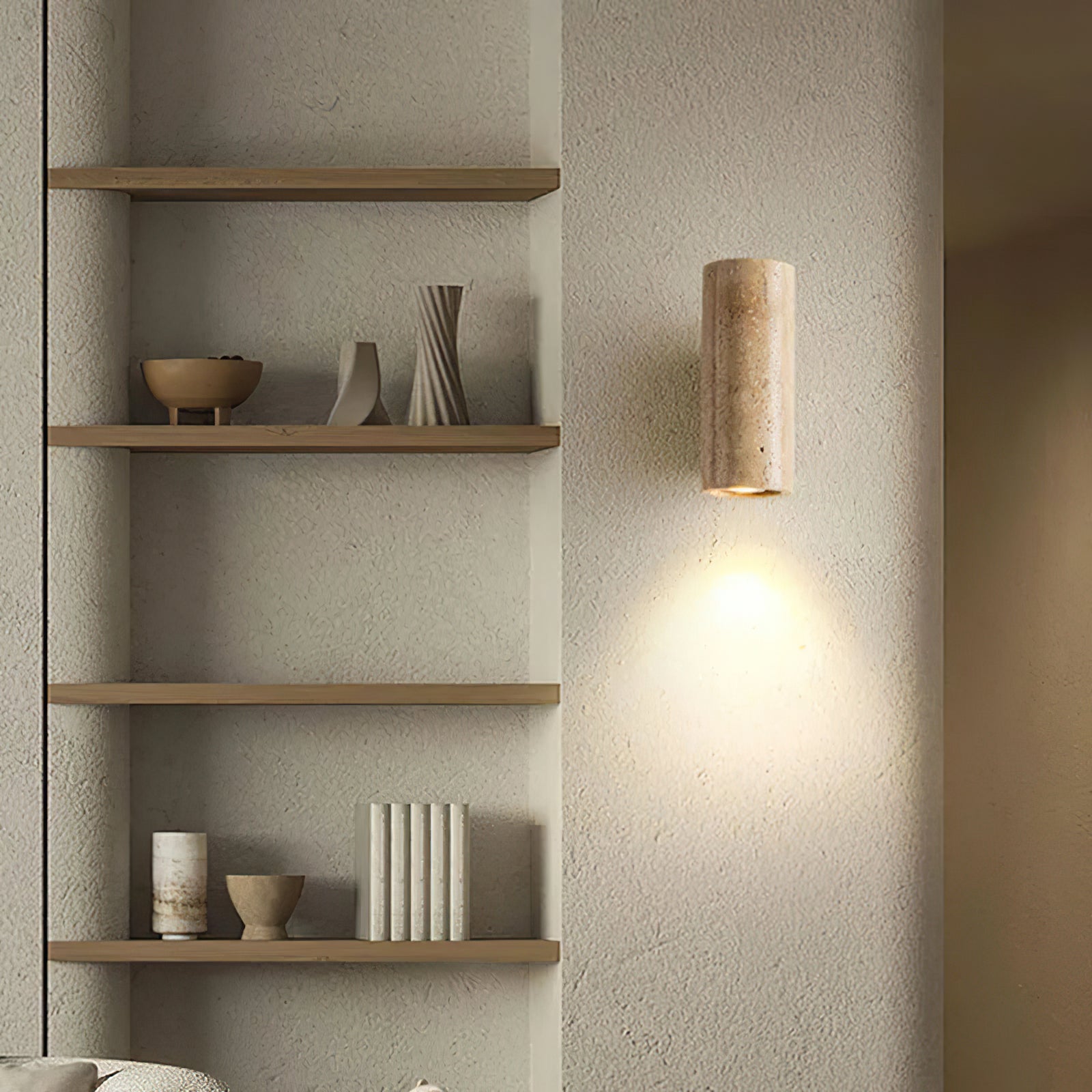 Stone cylinder sconce casting light beside open shelving