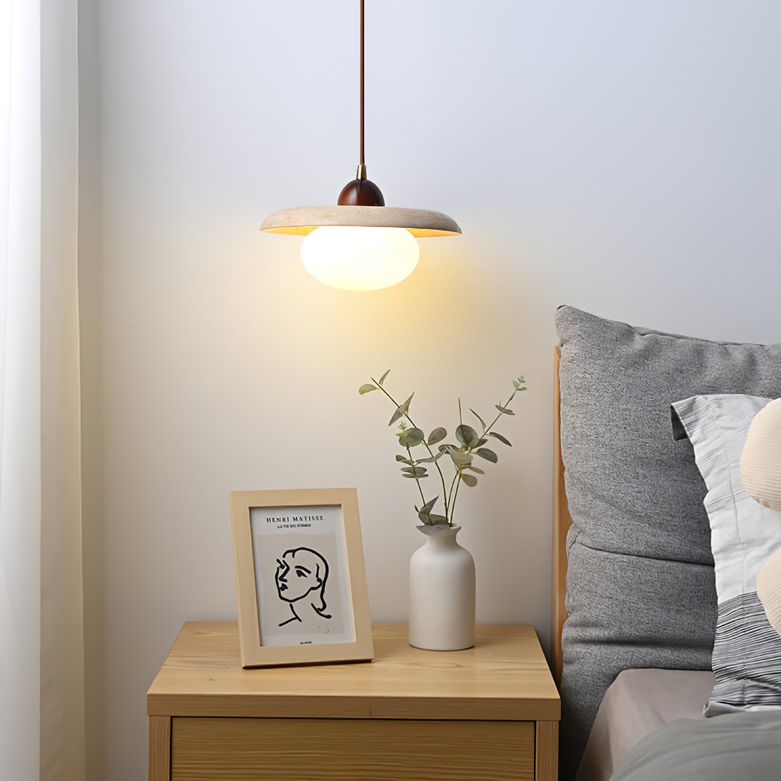 Glowing travertine pendant above a bedside cabinet