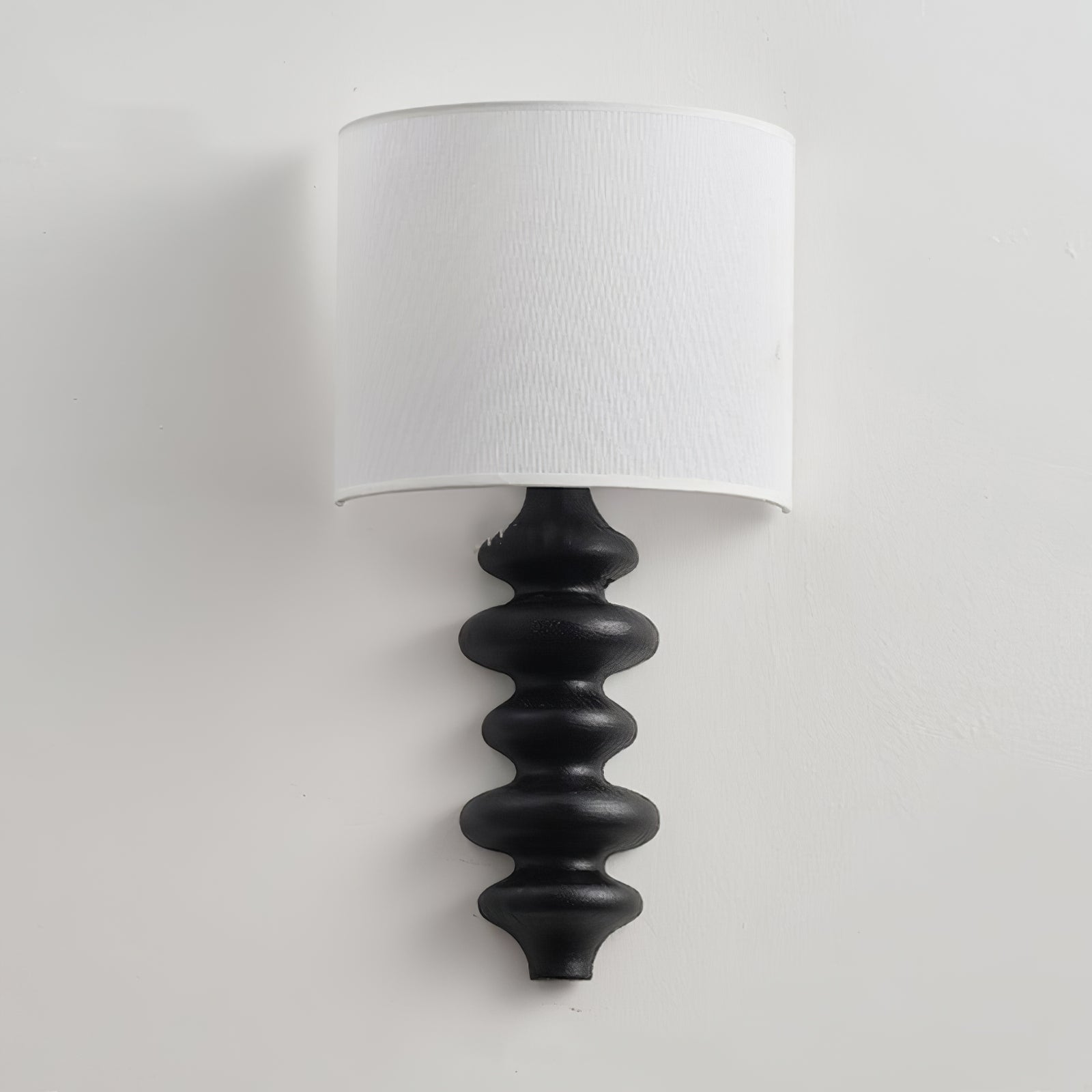 Unlit black-column Fishbone wall lamp against a pale wall