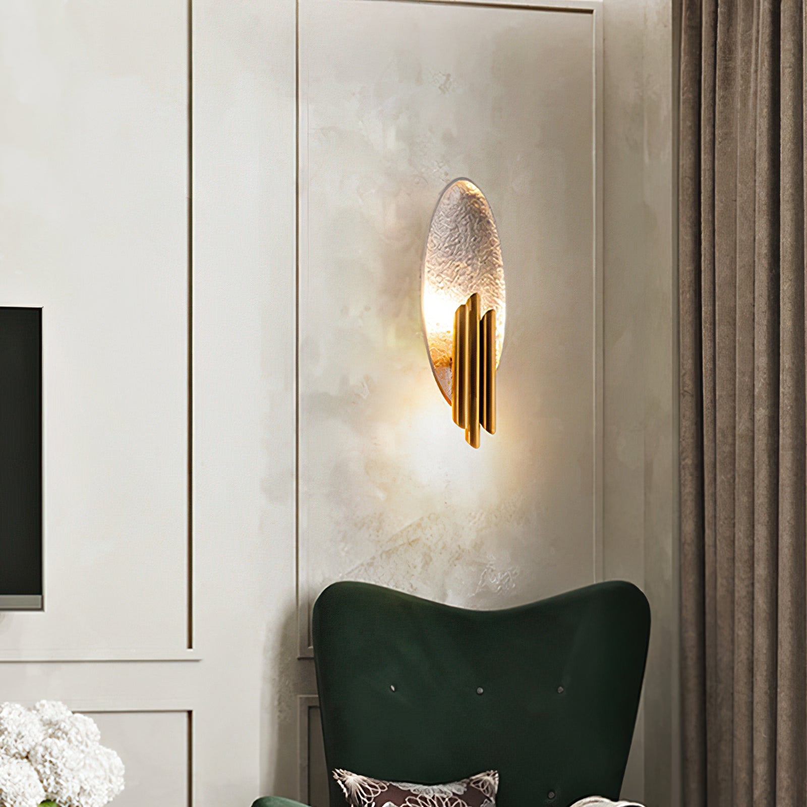 Silver-and-gold oval wall lamp above a green chair