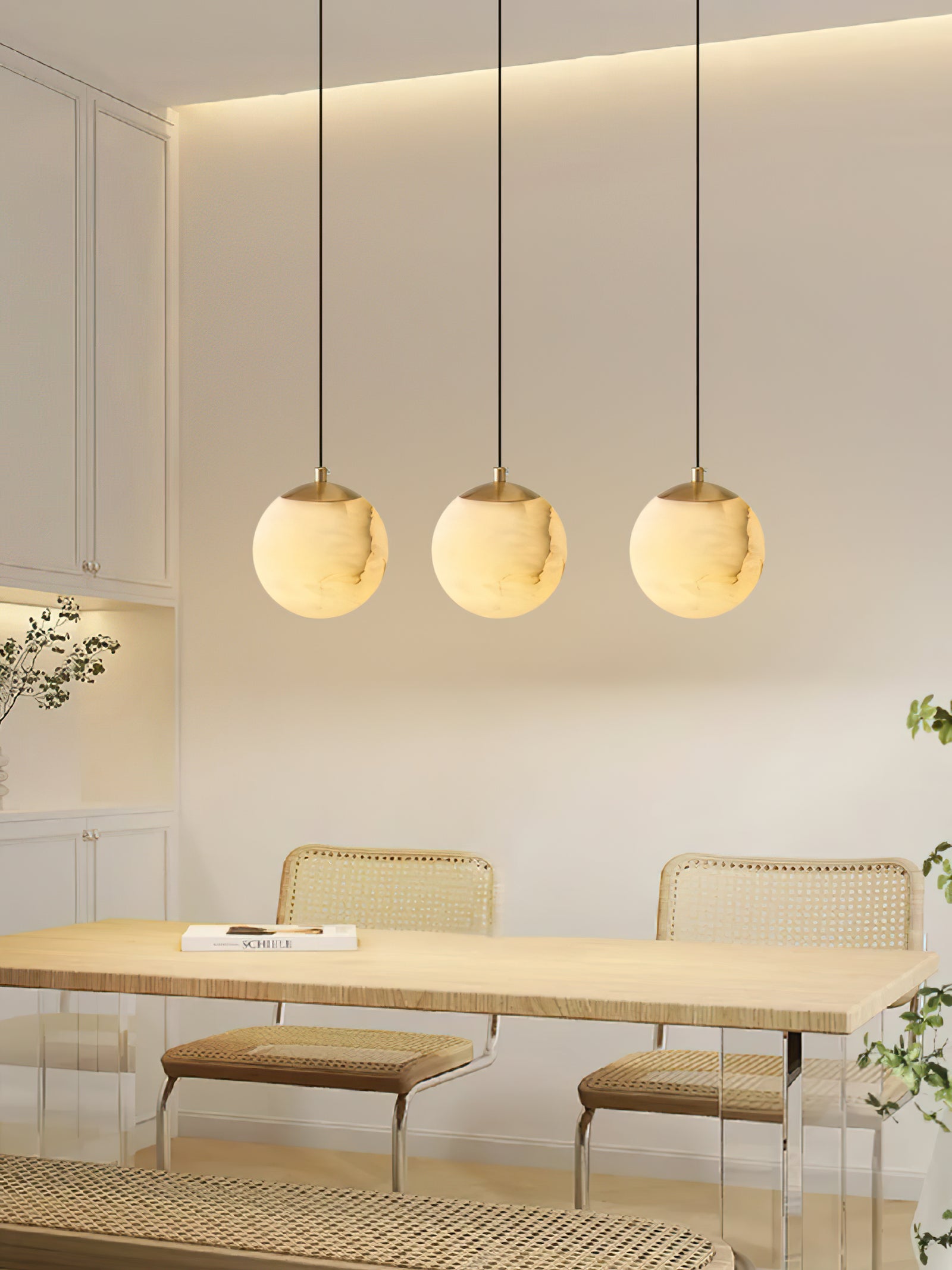 Three illuminated globes in a row above a dining table