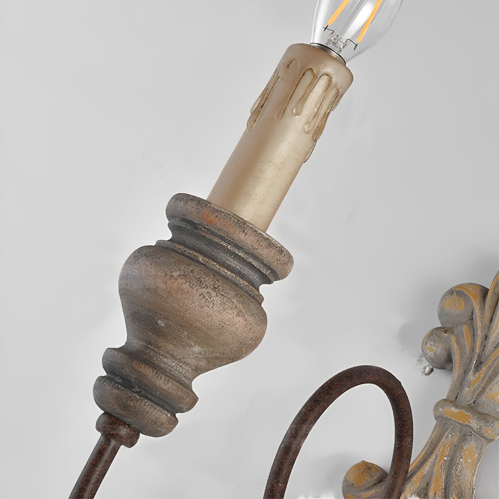 Close-up of the candle sleeve, holder and curved arm of the country wall lamp