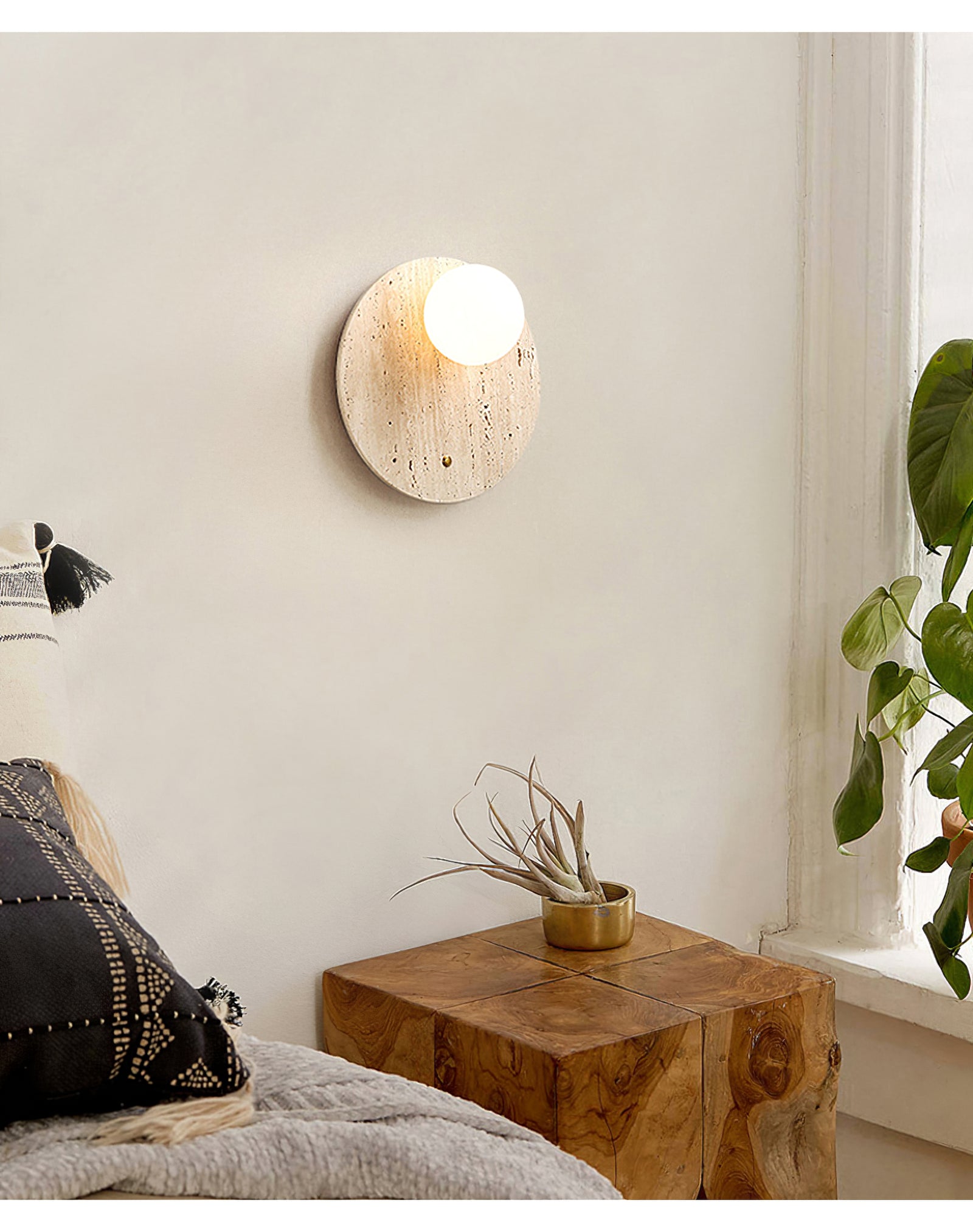 Lit travertine wall light above a wooden bedside table
