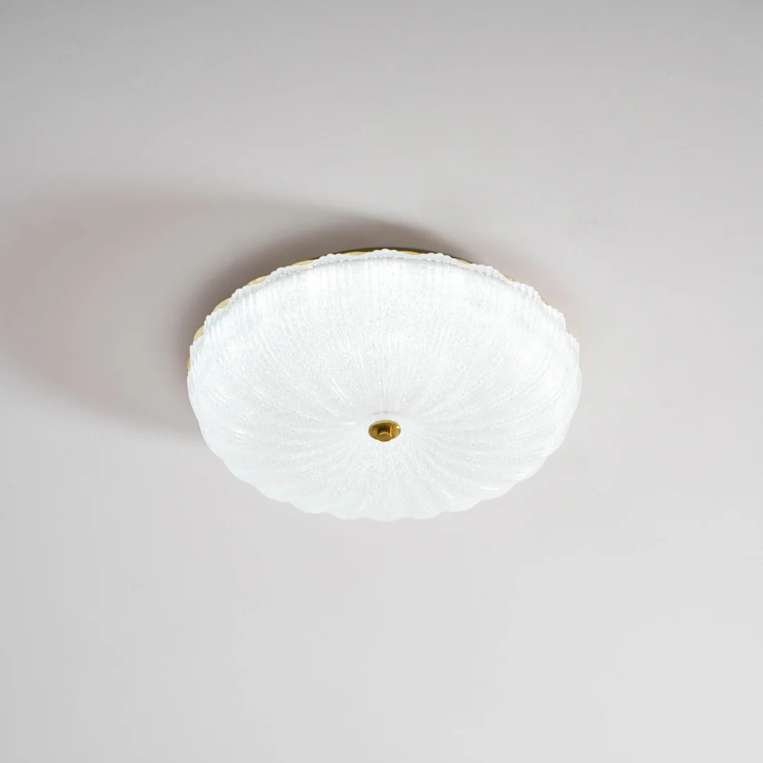 Ripple ribbed glass ceiling light brightly illuminated against a pale ceiling