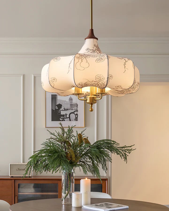 Patterned fabric pendant suspended above greenery and a sideboard