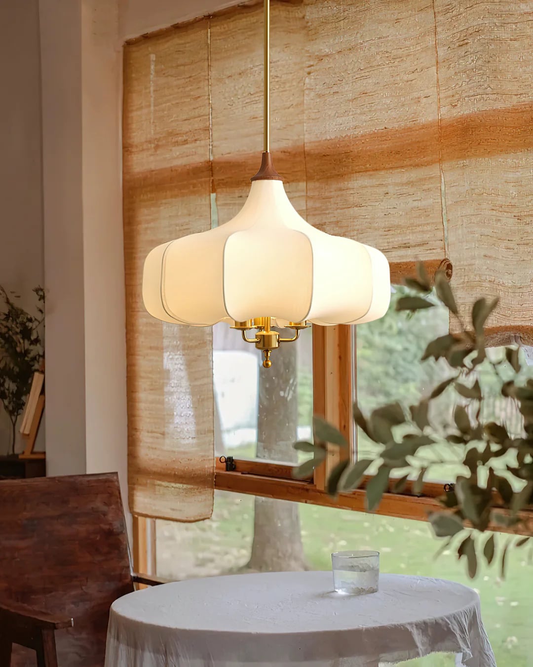 Plain fabric pendant above a round table in front of a bamboo blind