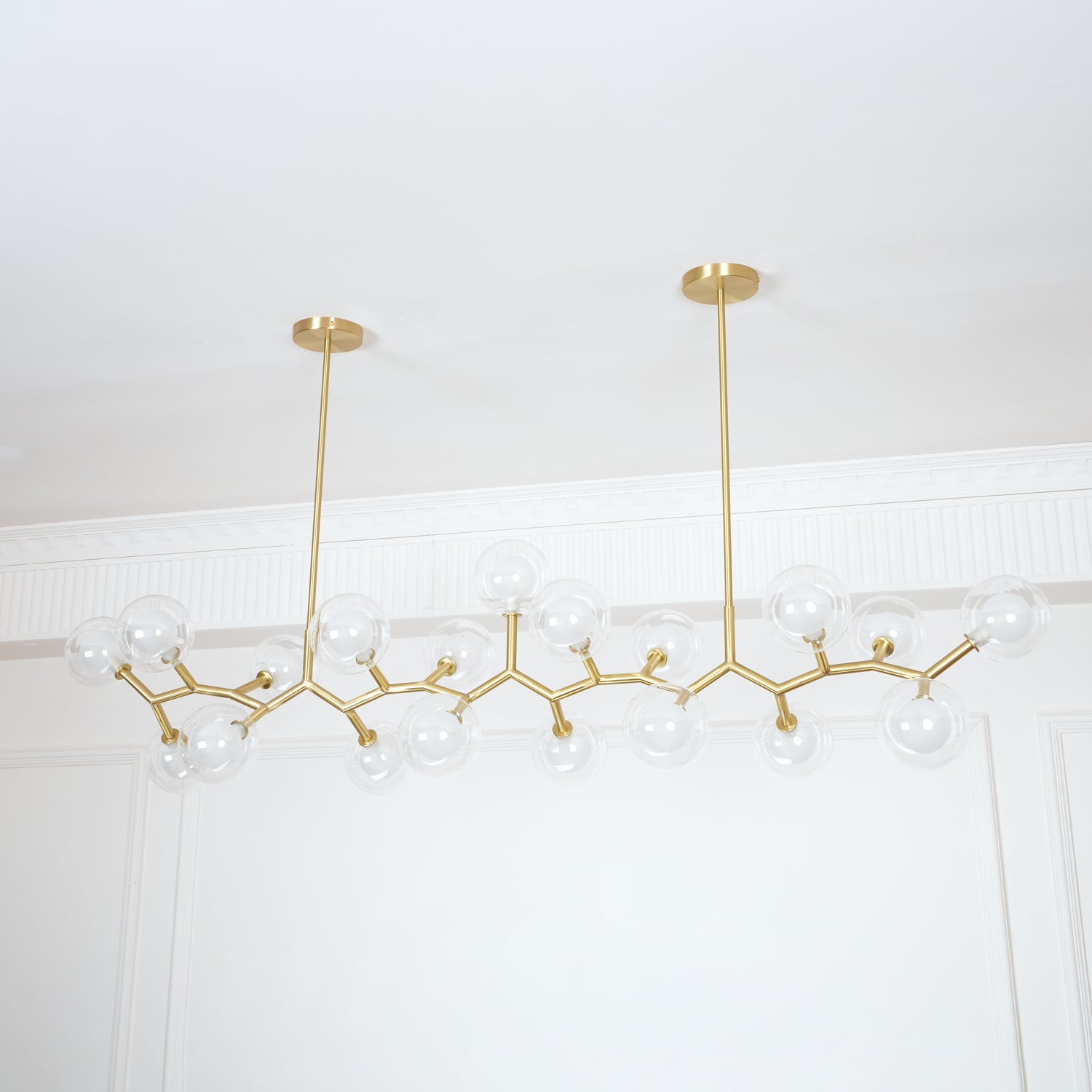 Two ceiling supports above an unlit glass-globe chandelier