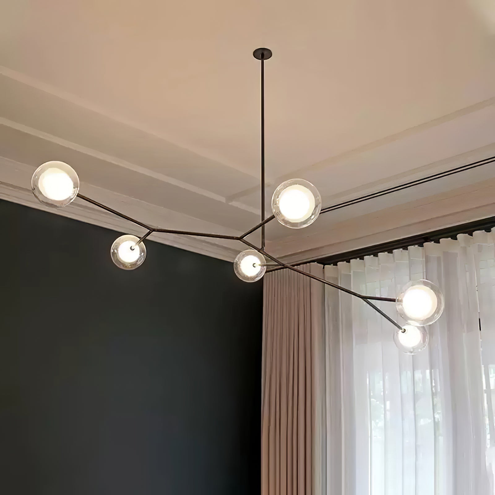 Branching globe chandelier beside full-height curtains