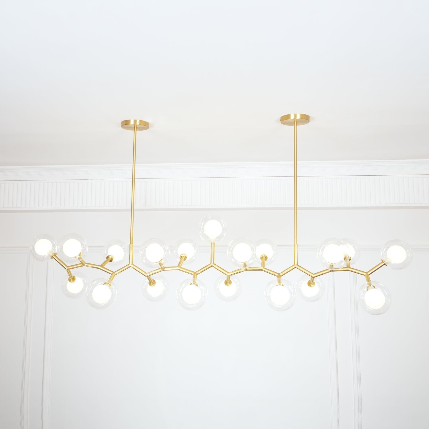 Gold branch chandelier and paired ceiling plates in a pale room