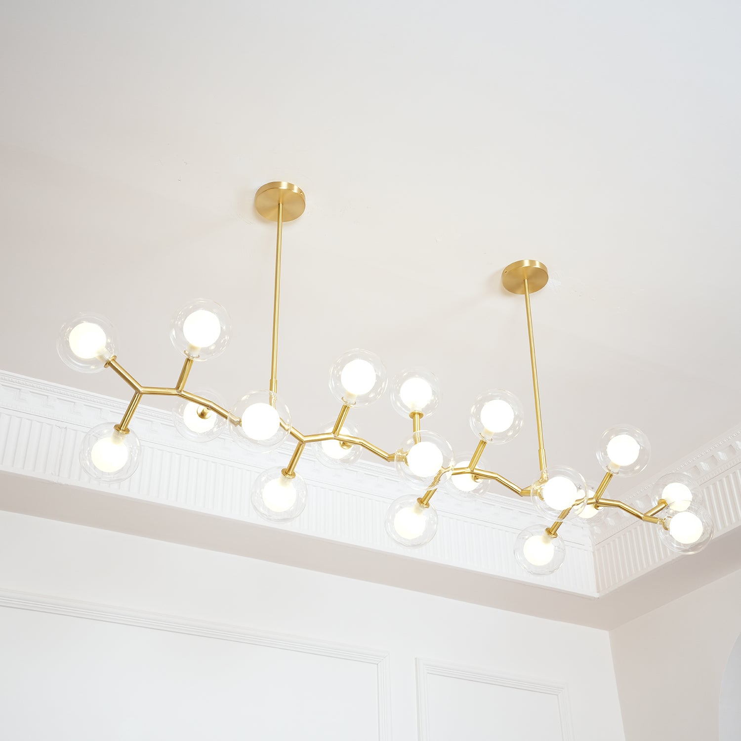 Illuminated branching chandelier against white ceiling mouldings