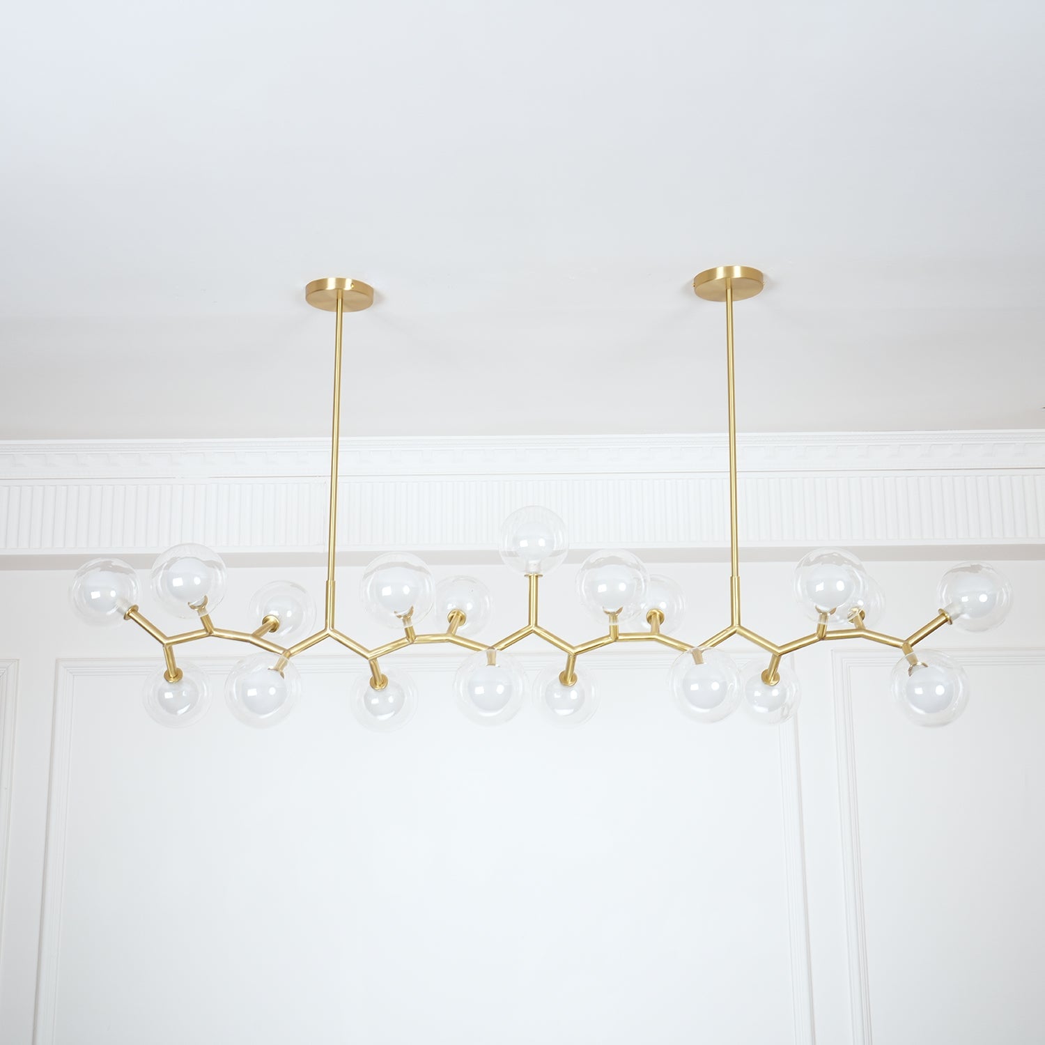Long gold frame and clear glass globes beneath two ceiling plates